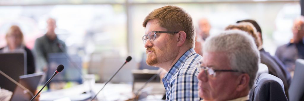 One Commissioner speaks at a microphone during a Commission meeting.