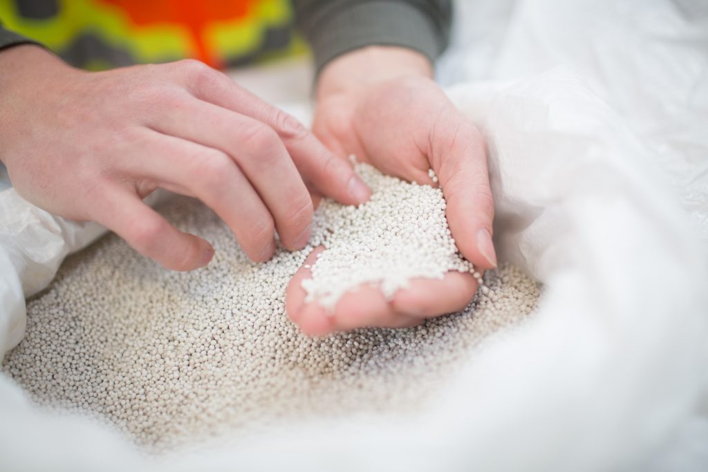 Close up of hands holding Ostara phosphorus pellets from a bag.