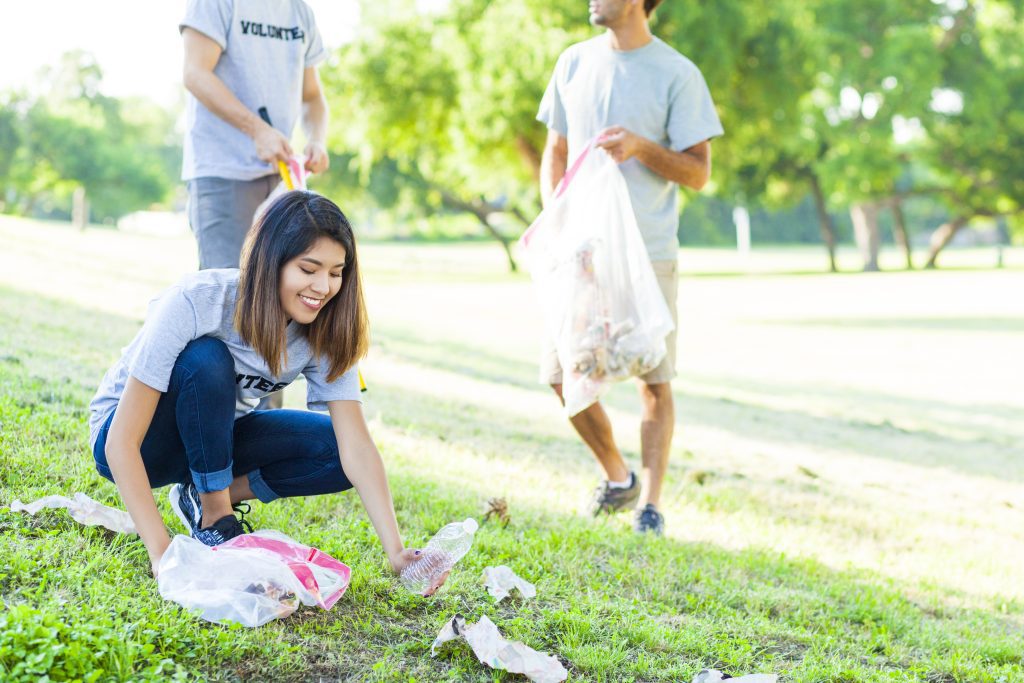 Young Woman Picks Up Trash In Park