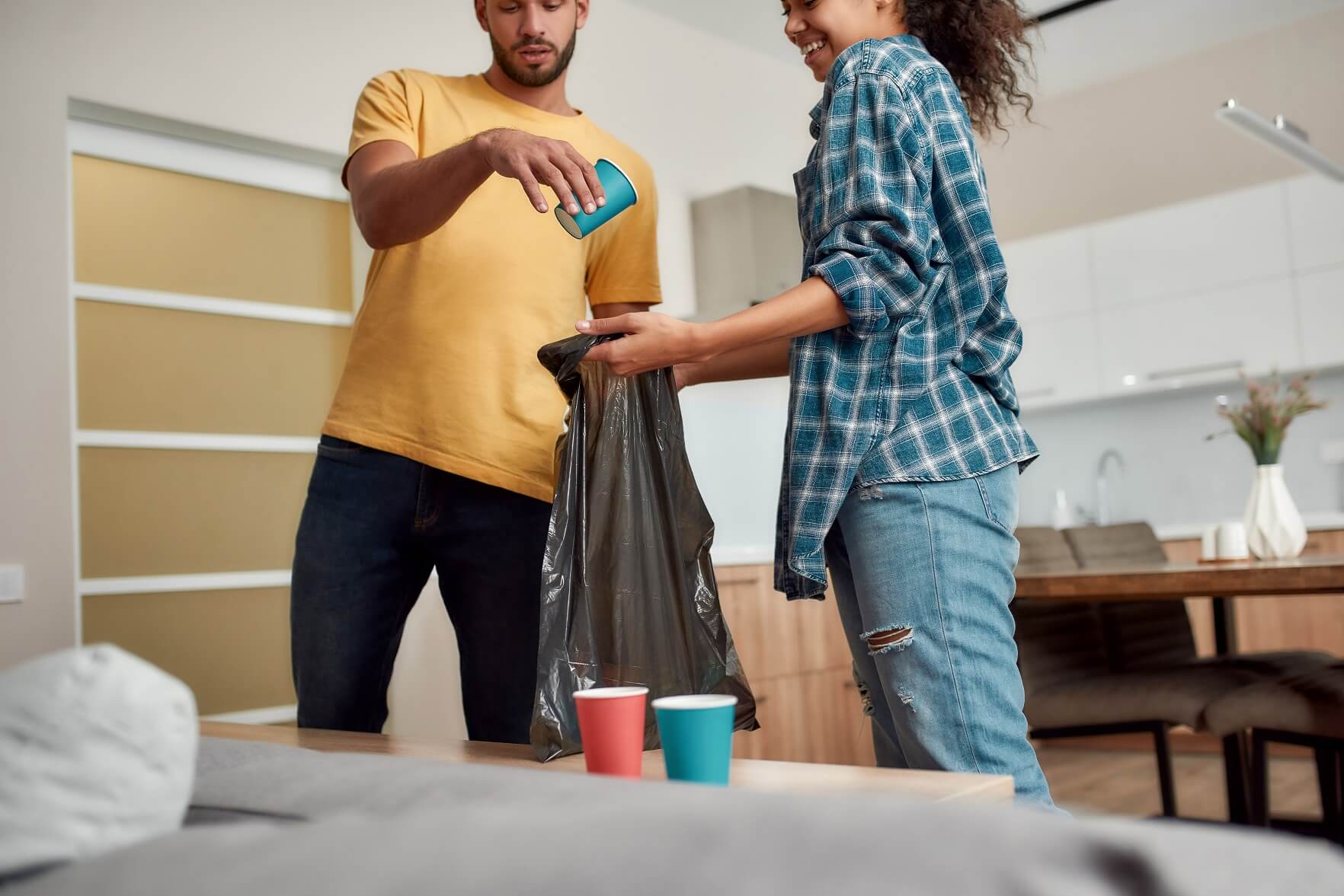 Young multicultural couple sorting garbage while cleaning their home kitchen and recycling non-flushables.