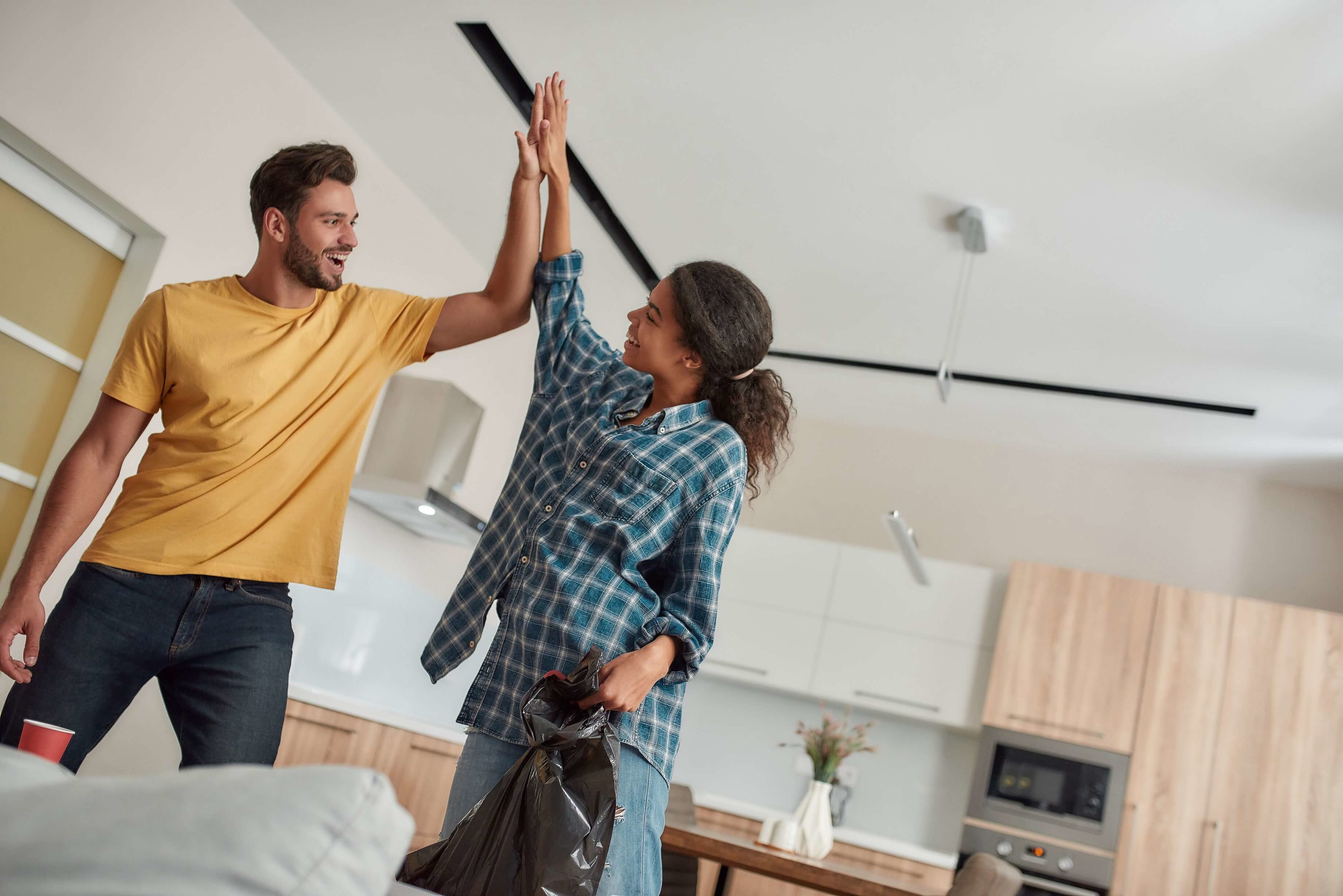 A Clean Home Is A Happy Home. Young Multicultural Couple In Casual Clothes Giving High Five While Cleaning Their Modern Kitchen Together