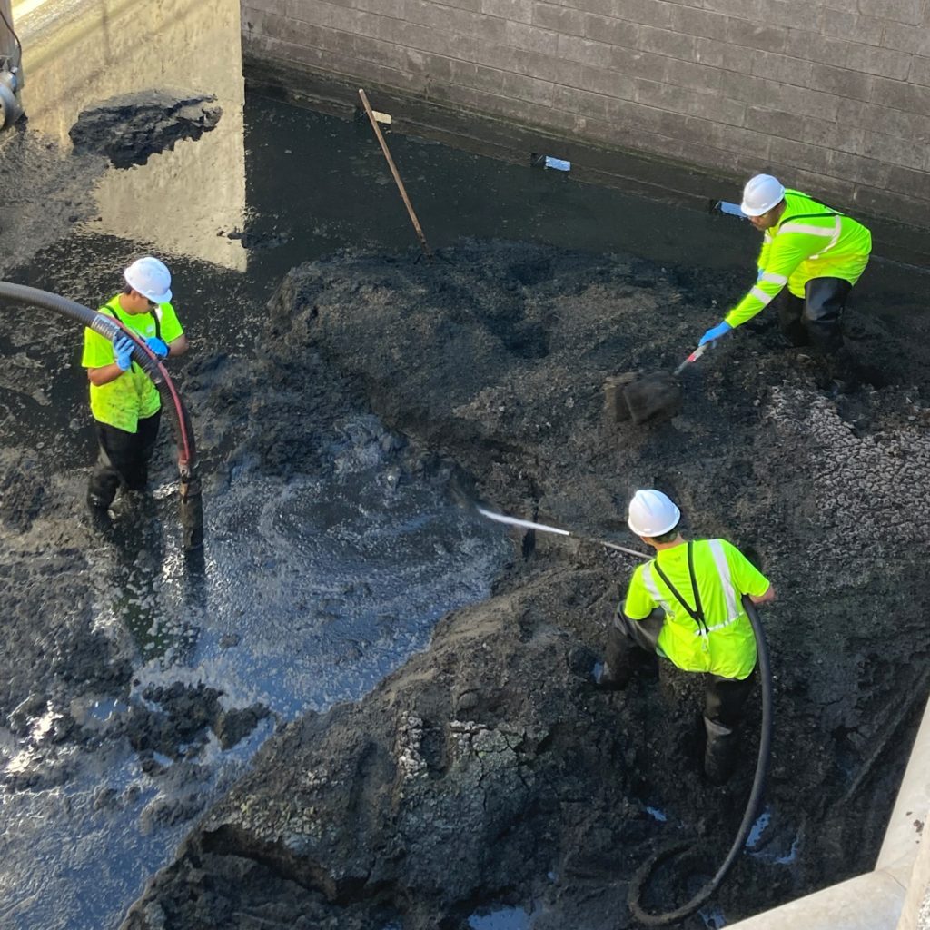 The team works on removing grit and snails from the bottom of an aeration tank.