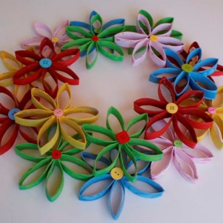 Homemade wreath made of painted TP rolls in a flower shape, adorned with contrasting colored buttons.