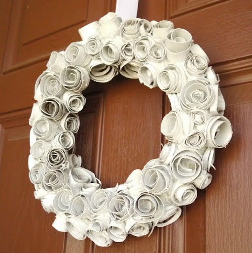 Wreath covered with flowers made from toilet paper rolls.