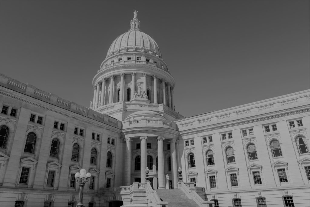 Black and white exterior photo of the Wisconsin State Capitol Building and its dome in Madison, WI.