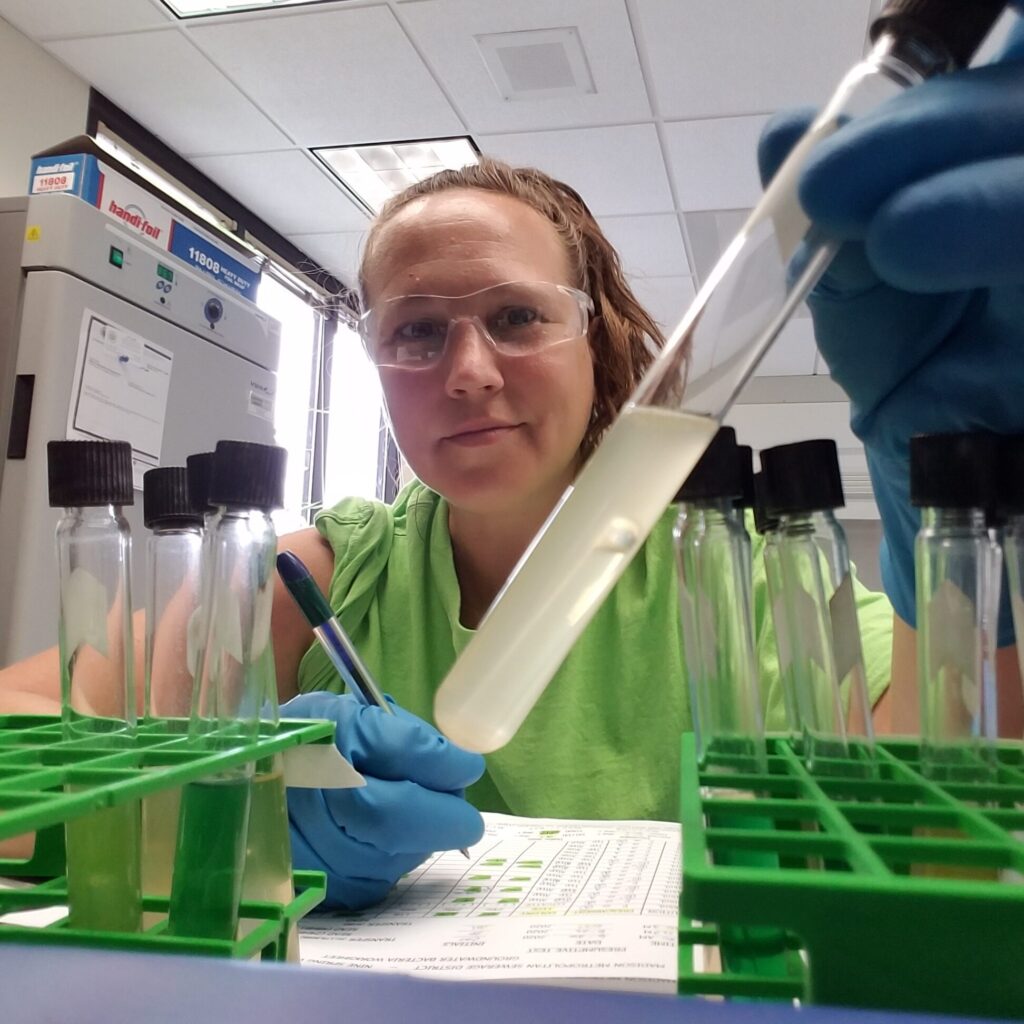 Operator Brenda Staudenmaier holds a test tube of a wastewater sample for testing in the lab.