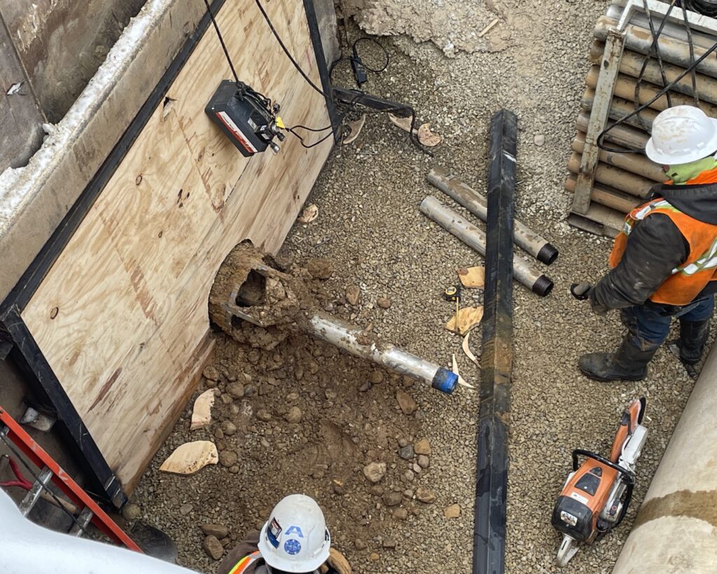 View of the transition from pilot tube to 16-inch auger casing pipe in the receiving pit. Above is the reamer head transition.