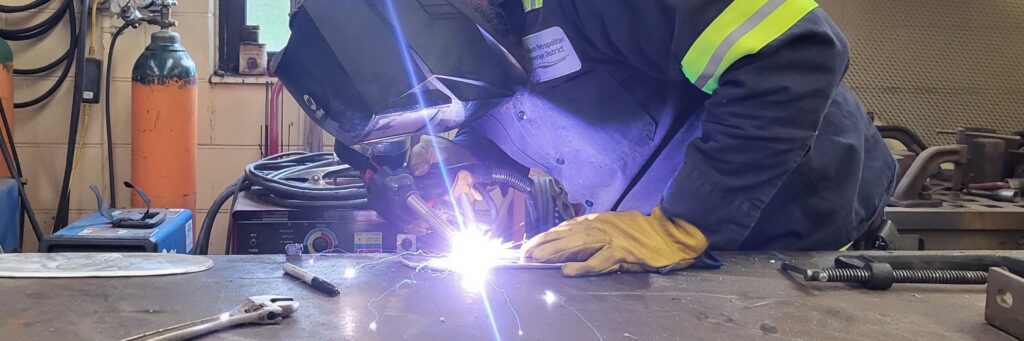 A mechanic welds a part for a maintenance project.