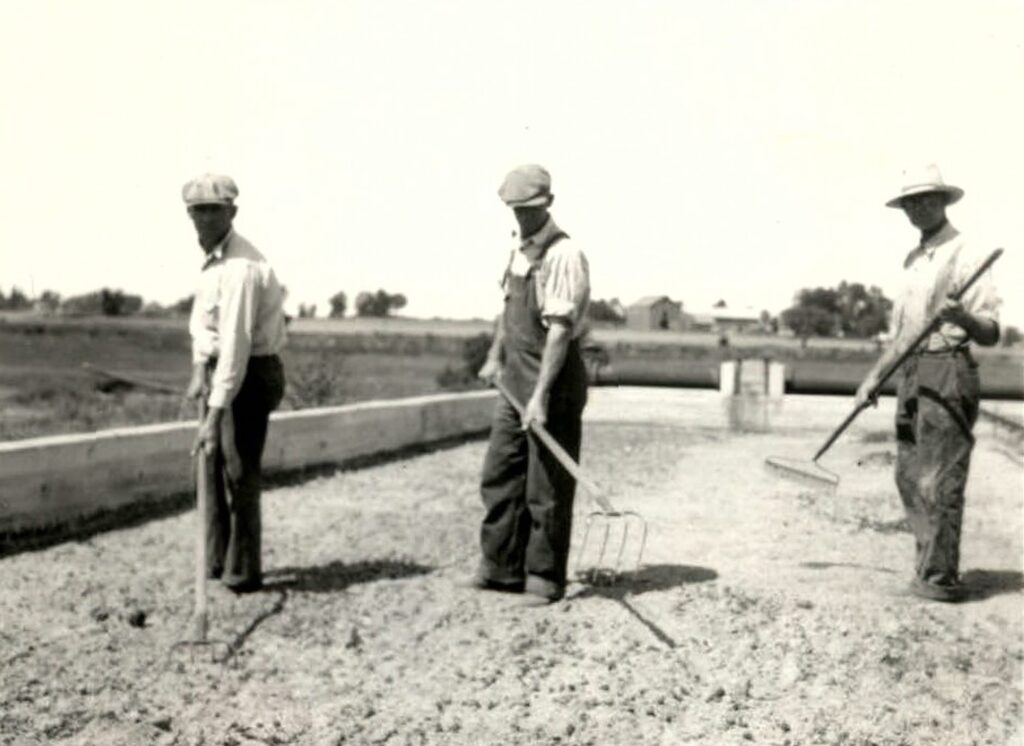 District staff rake the sludge in the drying bed.