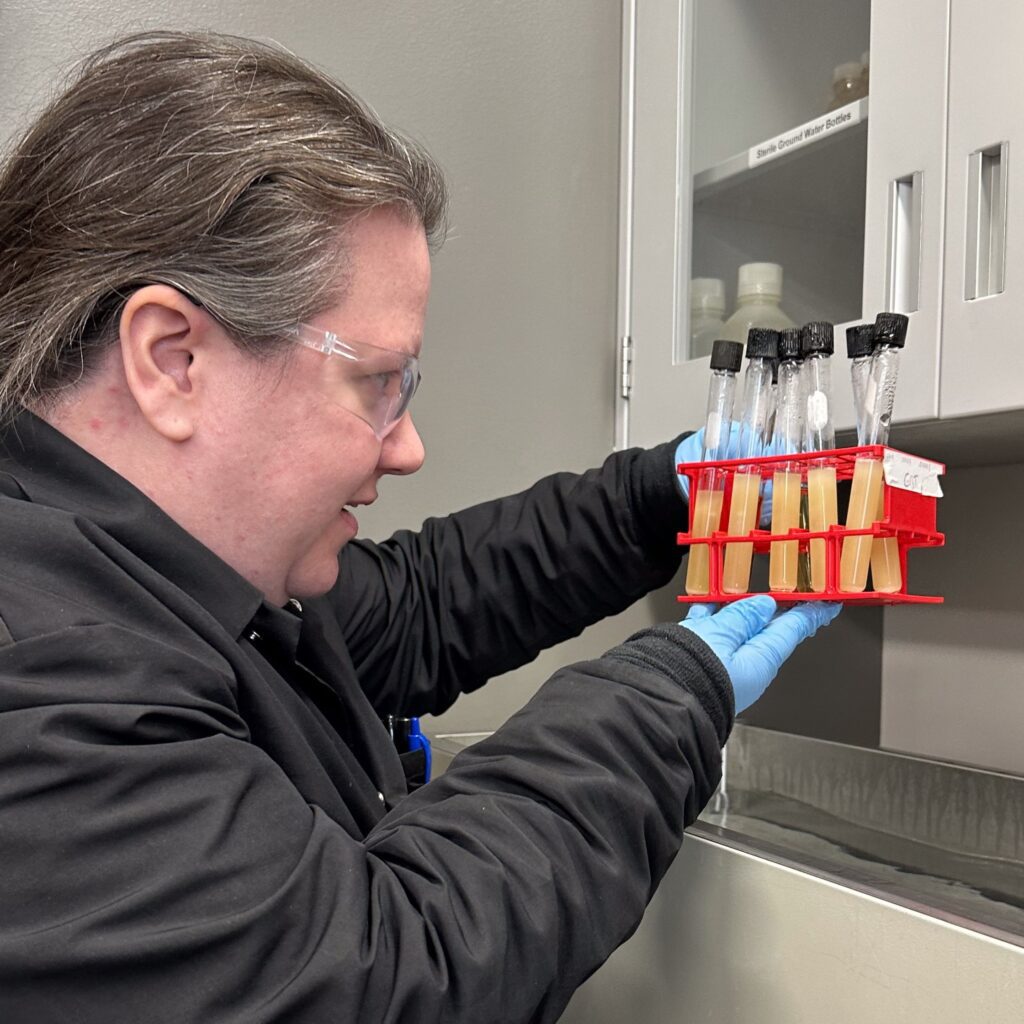 A female chemist holds test tubes of Metrogro biosolids in the lab.