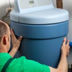 A professional inspector or plumber looking at or installing a water softener tank.