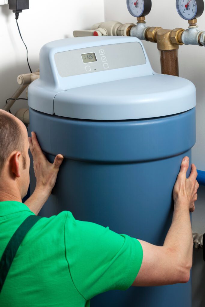 A professional inspector or plumber looking at or installing a water softener tank.