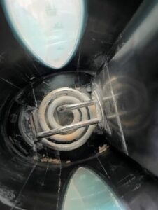 The exposed heating element or coil in an electric kettle, showing signs of white scale buildup.