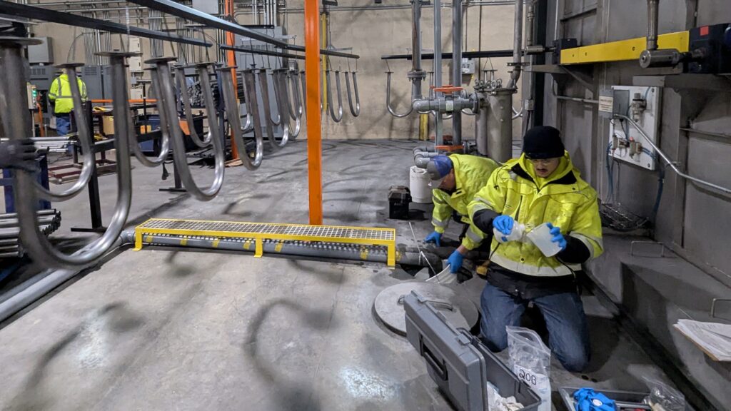 CSS lead Mike Kressing and CSS crew member Griffin Bohm collect wastewater samples near the bike rack production line at Graber.