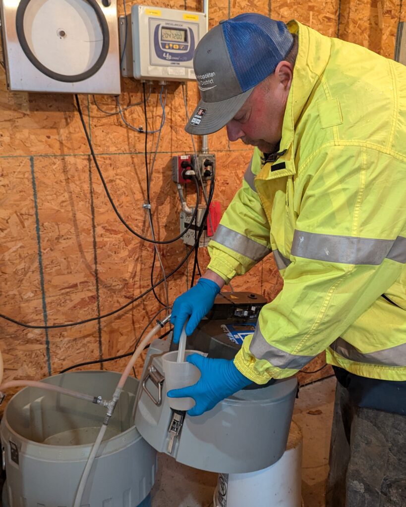 Having first set up a sampler a day earlier, CSS crew lead Mike Kressin retrieves a composite sample from the sampler at Scientific Protein Laboratories, a biopharmaceutical manufacturing facility.