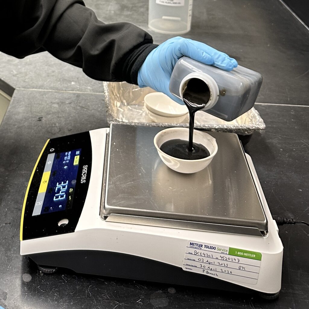 A chemist pours a sample into a crucible on a scale.