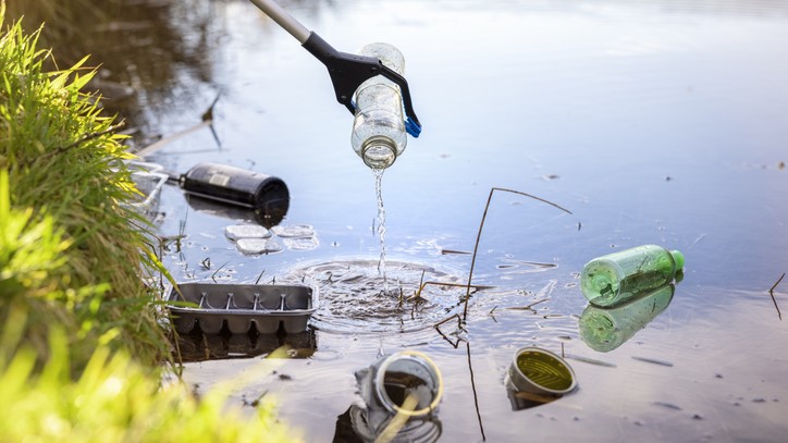 A grabbing device picks up litter in a waterway.