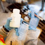 A scientist holds a sample and clipboard for PFAS testing.