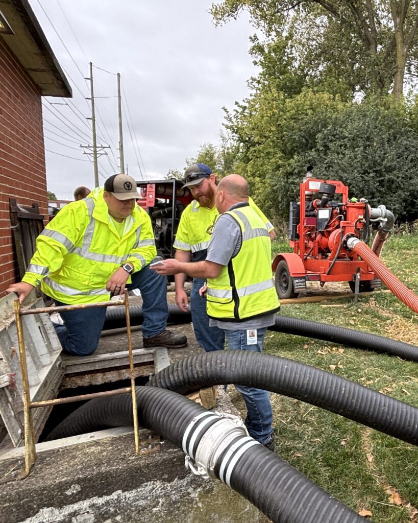 Brady Lessner talks with Dylan Konkel and James Dinges on the Facilities Maintenance team, who will monitor the PS 3 bypass pumping overnight.