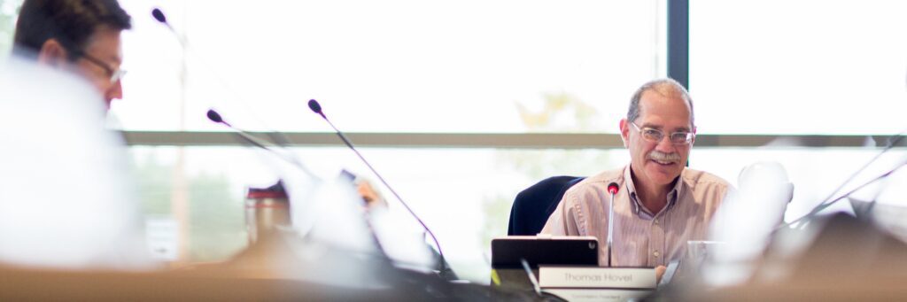 A photo of the Commission president sitting at the meeting table in front of a microphone.