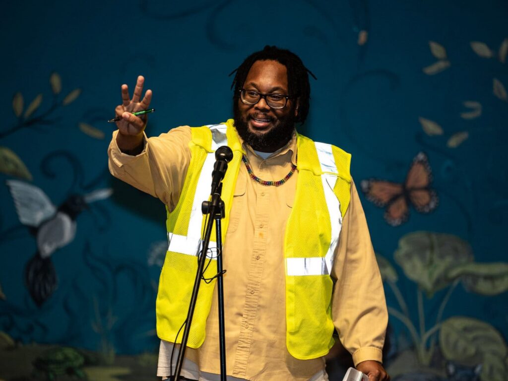 2023 artist/educator in residence Charles Payne at a microphone for the "By the Water" Story Slam event.