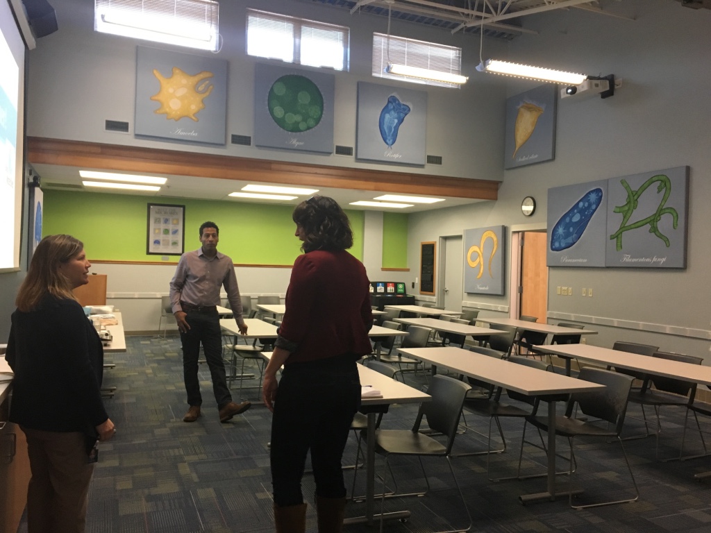 Three people talk in an empty water science educational classroom.